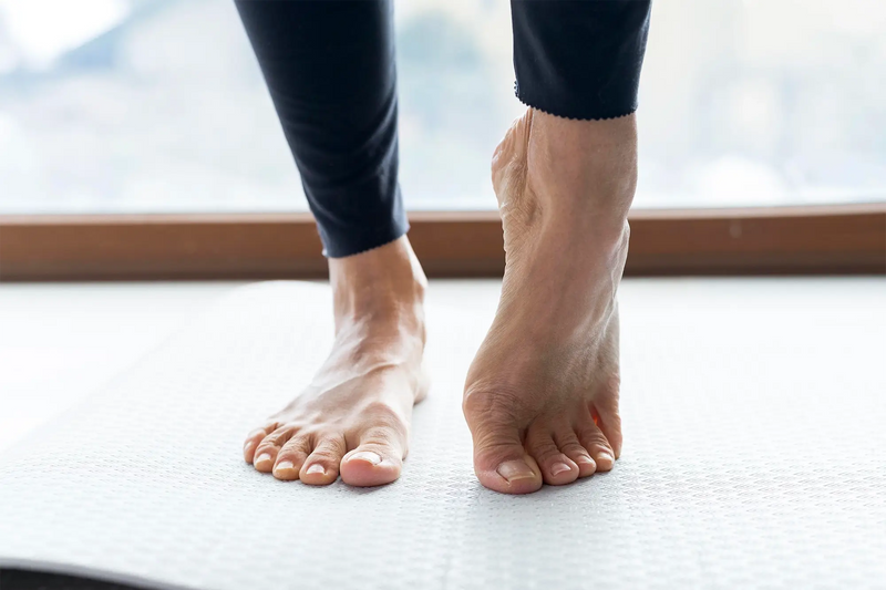 Füße einer Person, die auf einer Yogamatte balanciert